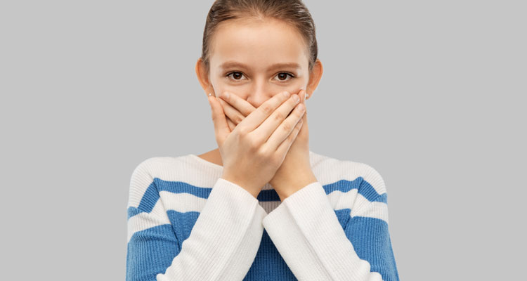 Teenage girl covering mouth by hands